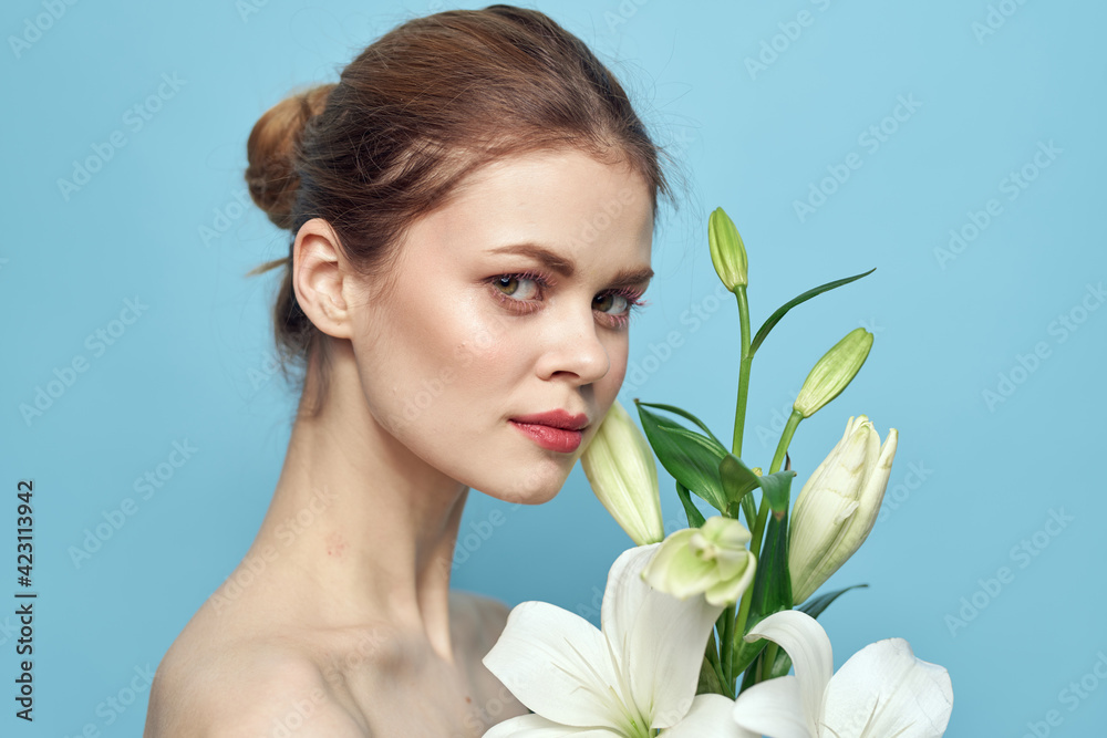 Beautiful girl with a bouquet of white flowers on a blue background cropped view naked shoulders portrait Beautiful girl with a bouquet of white flowers on a blue background cropped view naked shoulders portrait