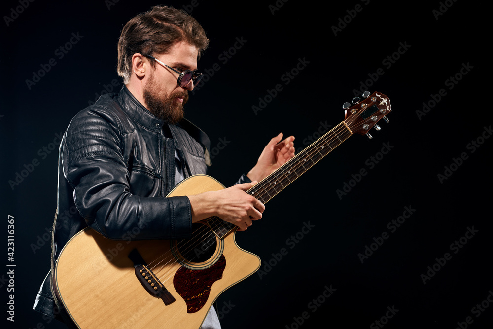 Naklejka premium A man with a guitar in his hands leather jacket music performance rock star modern style dark background