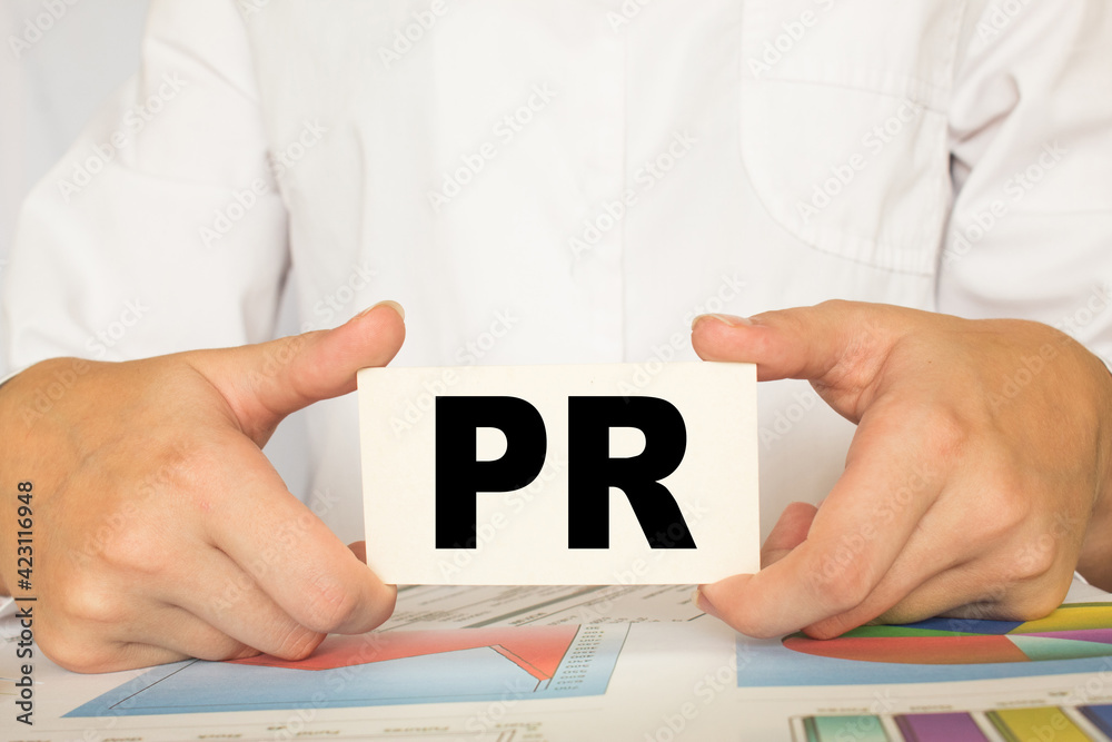 a man in the office holds a card with text PR . business concept a man in the office holds a card with text PR . business concept