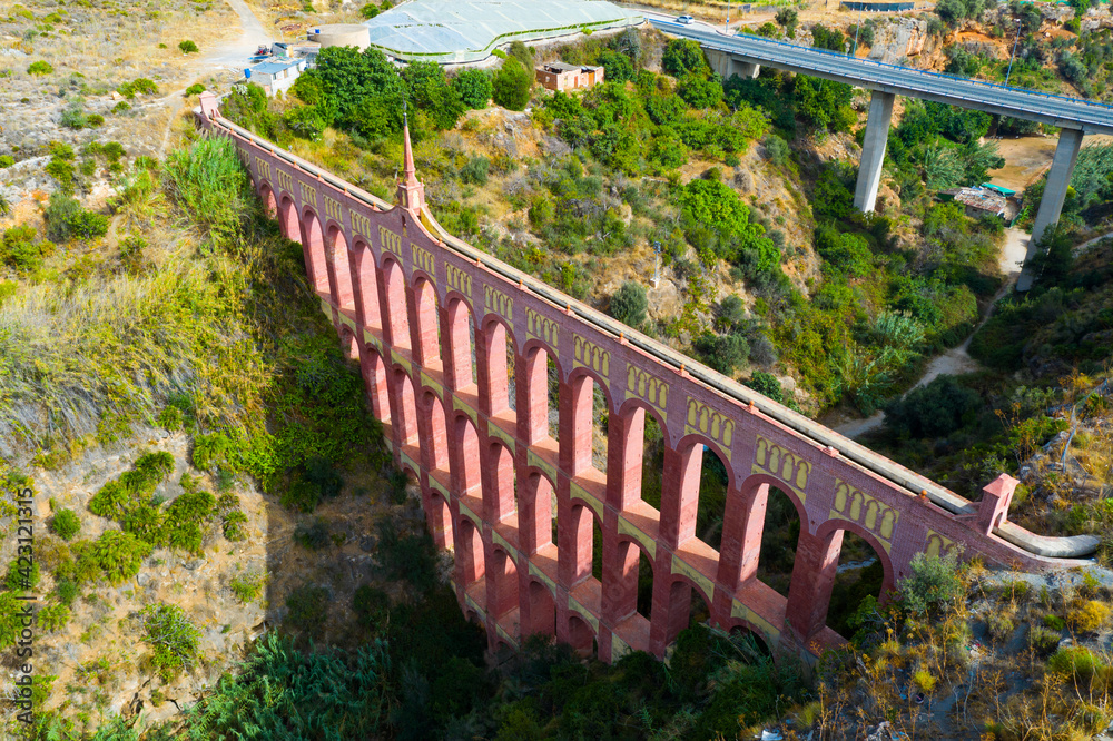 Scenic aerial view of Aqueduct of Eagle, four storied arch bridge over canyon of Barranco de la Coladilla on sunny fall day, Nerja, Spain..