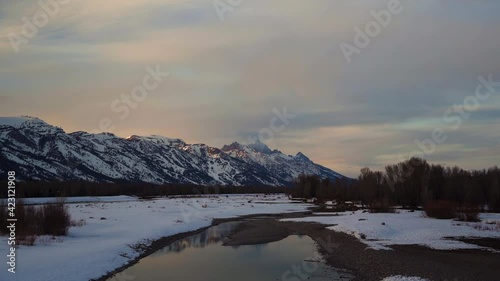 Grand Teton mountains in national park with alpenglow and snowy river with reflection from icy river in Wyoming United States prores 4k