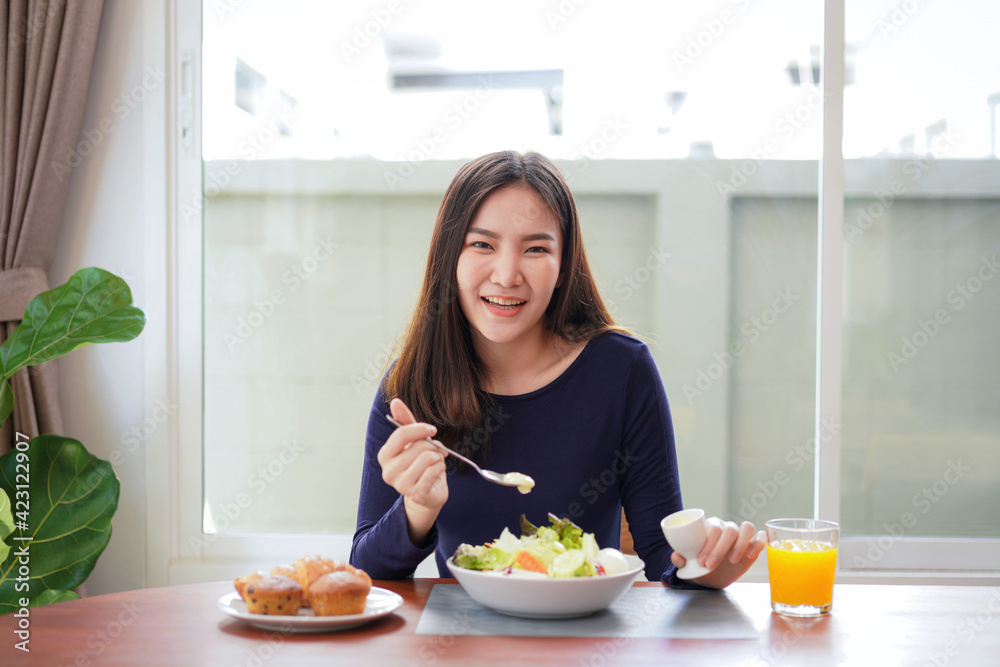 Young asian woman use a salad dressing spoon to mixing with fresh vegetable on wellness lifestyle Young asian woman use a salad dressing spoon to mixing with fresh vegetable on wellness lifestyle
