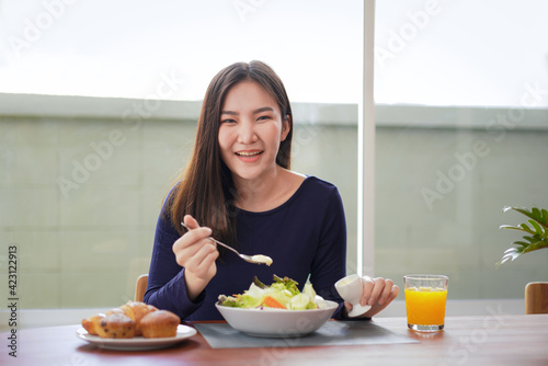 Young asian woman use a salad dressing spoon to mixing with fresh vegetable on wellness lifestyle