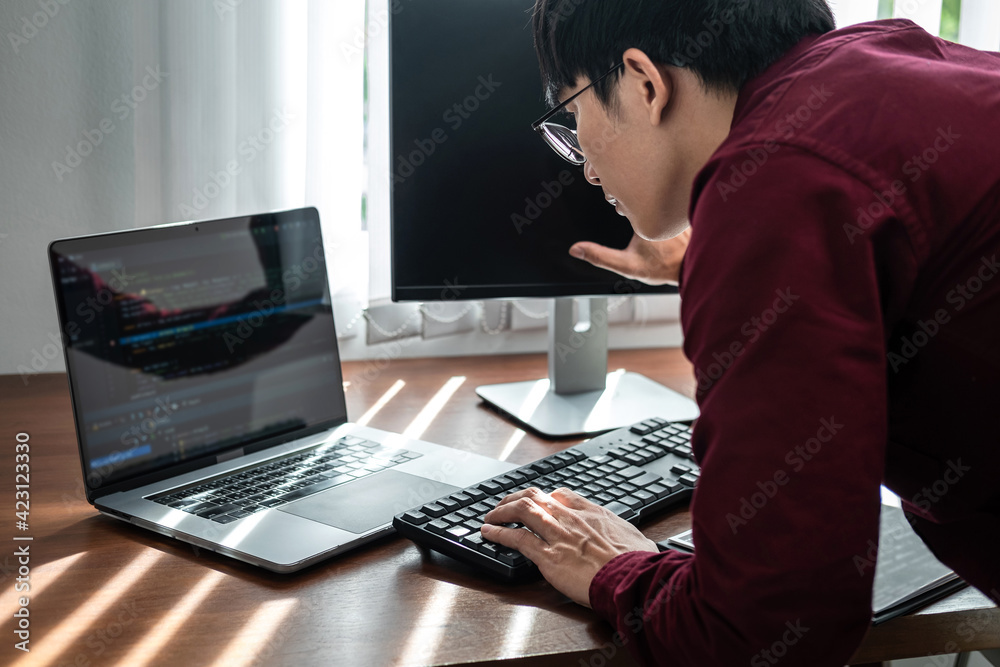 Asian man programmer looking and touching on screen laptop to typing code data with keyboard about website Asian man programmer looking and touching on screen laptop to typing code data with keyboard about website