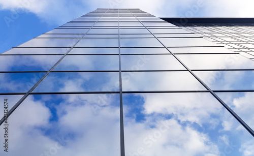 View of a modern glass skyscraper. Reflection of a cloudy blue sky in a glass skyscraper