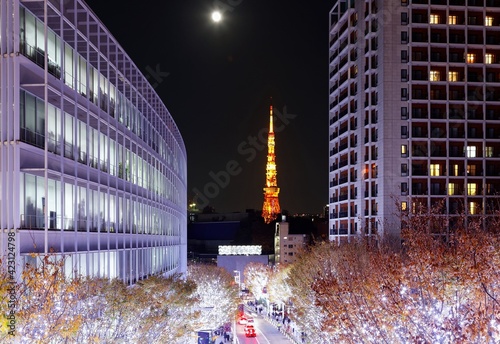 Romantic Winter Illumination Display at Christmas Season in Keyakizaka, viewed from Roppongi Hills, with a street flanked by illuminated buildings & trees & landmark Tokyo Tower glowing in background photo