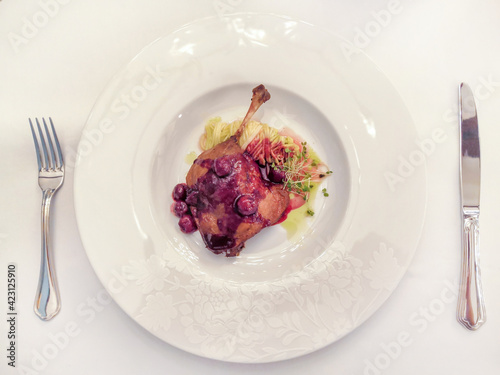 served table in a restaurant, leg of duck with cherry sauce, selective focus