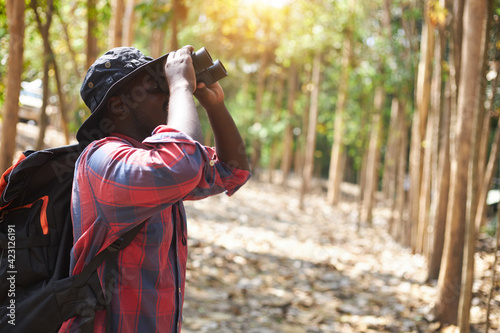 African male tourist is using binoculars in the wild.