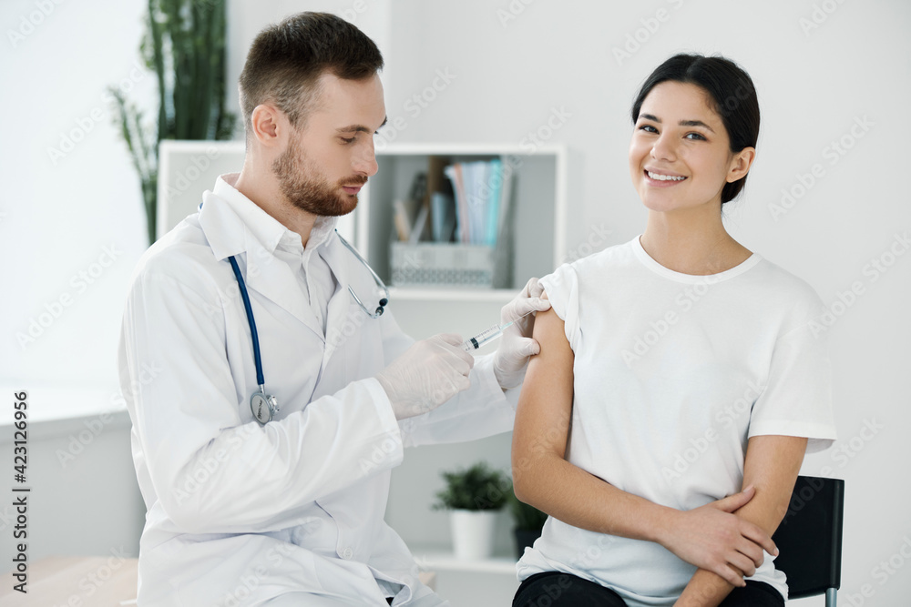 the doctor injects the vaccine into the patient's shoulder hospital and protective gloves infection