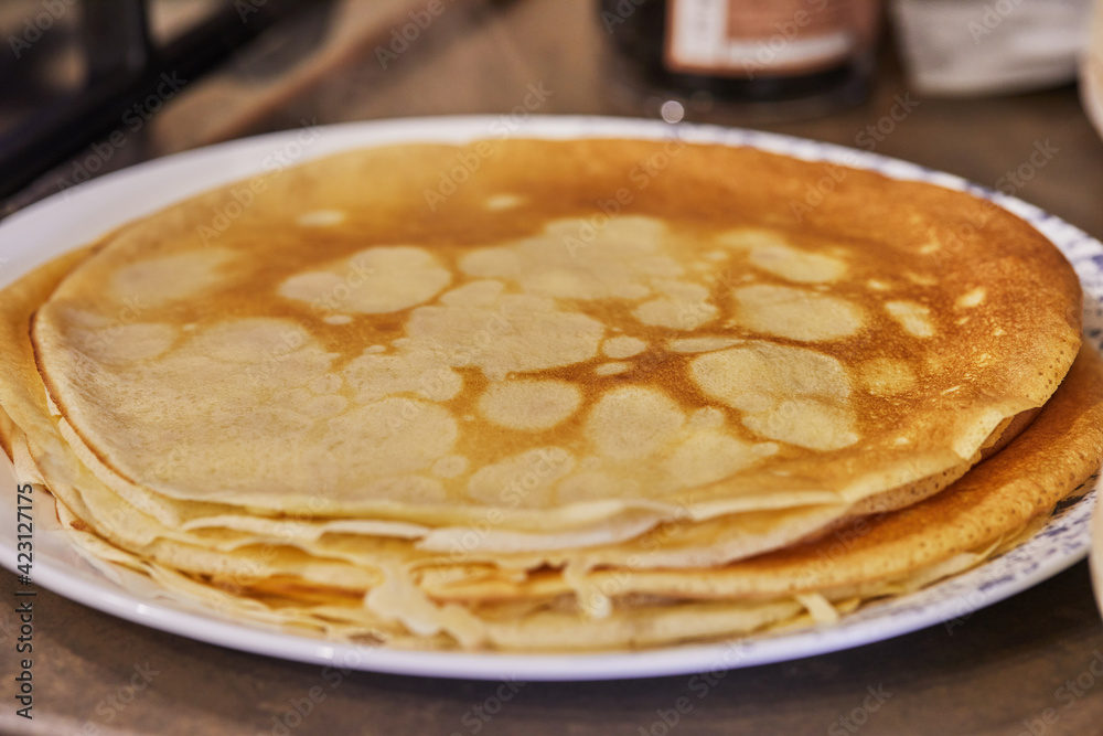 A stack of ready-made pancakes on a white plate. Step by step recipe.