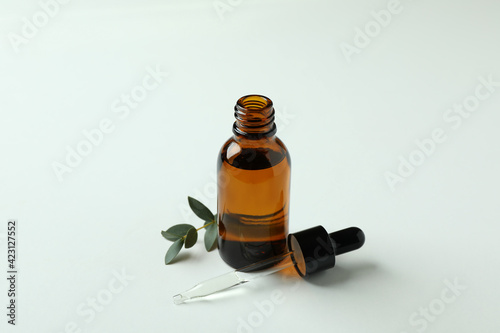 Brown bottle of eucalyptus oil and twig on white background