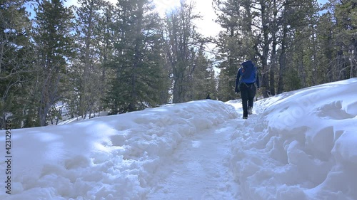 Hiker walking down a snow packed trail