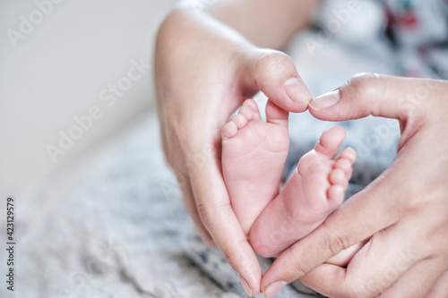 The baby s feet are in the hands of an Asian mother. Concept for love and health.