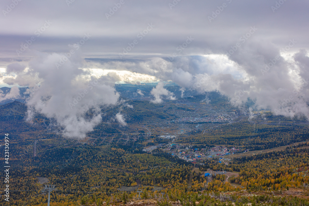 top view of a small industrial town in the mountains in autumn. Sheregesh in the morning in the clouds and fog before the ski season. ski resort