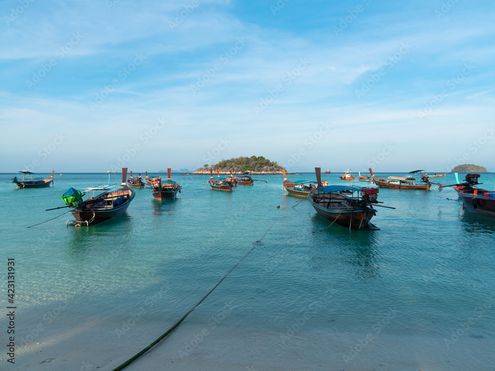 many wooden longtail boats on blue sea at Sunrise beach, Lipe Island