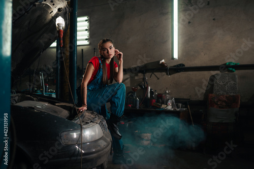 Female auto mechanic work in garage, car service technician woman check and repair customer car at automobile service center, inspecting car