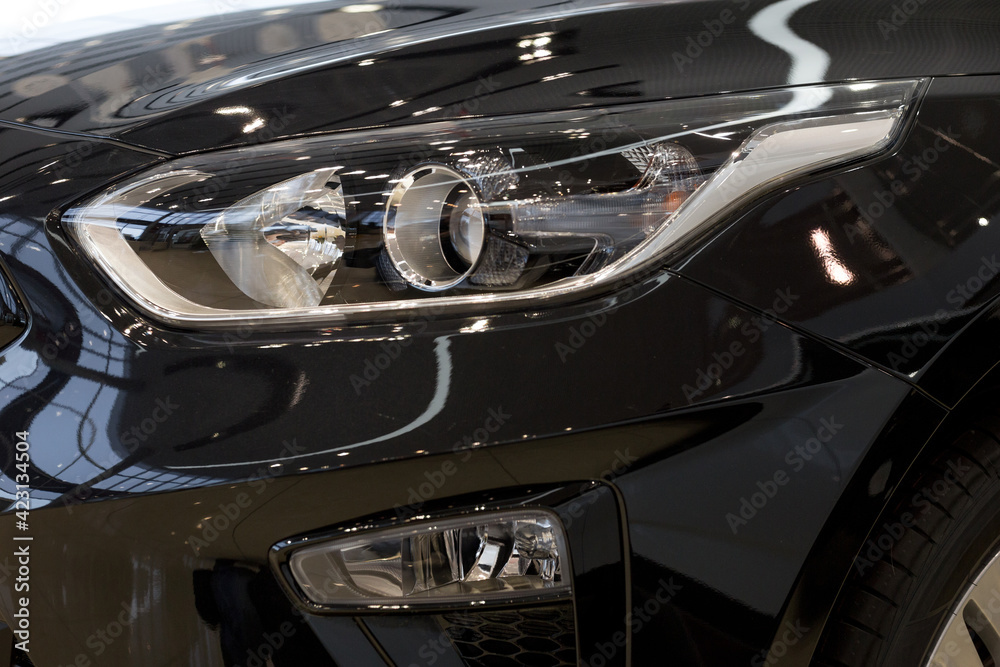 New modern unknown car with elegant head lamps. Cropped image. Close up.
