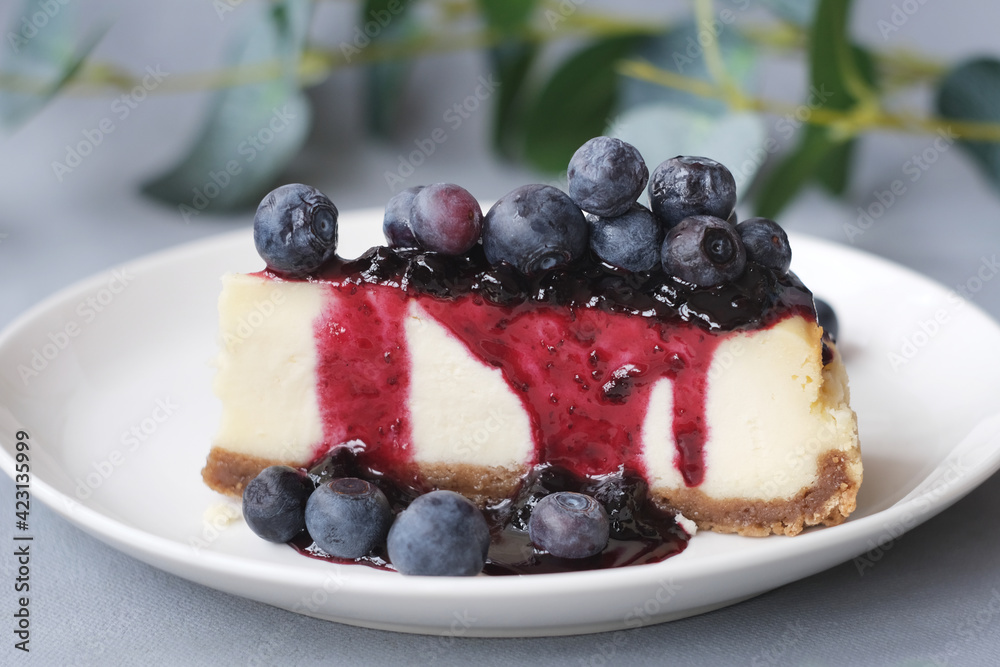 Portion of cheesecake with blueberry jam and fresh blueberries on plate. Sweet delicious homemade cake. Portion of cheesecake with blueberry jam and fresh blueberries on plate. Sweet delicious homemade cake.
