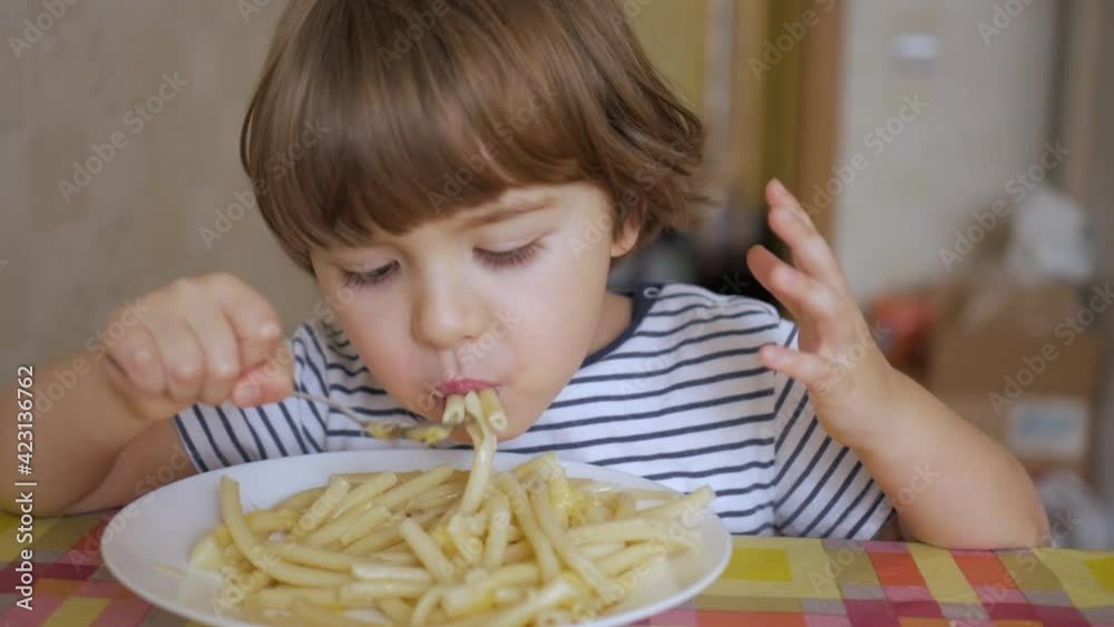 Cute Little Boy Eating Spaghetti With Cheese On Kitchen. Portrait Funny Healthy Preschool Kid Boy Eats Pasta Noodles. Hungry Child Eating With Hands And Smiling Healthy Food at Home. Cute Little Boy Eating Spaghetti With Cheese On Kitchen. Portrait Funny Healthy Preschool Kid Boy Eats Pasta Noodles. Hungry Child Eating With Hands And Smiling Healthy Food at Home.