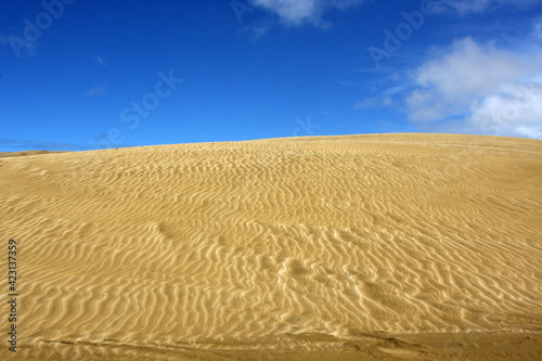 Sandy hill in the desert, dunes and blue sky background