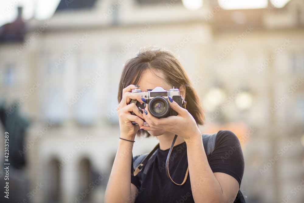  Young woman taking photo in the city with camera.