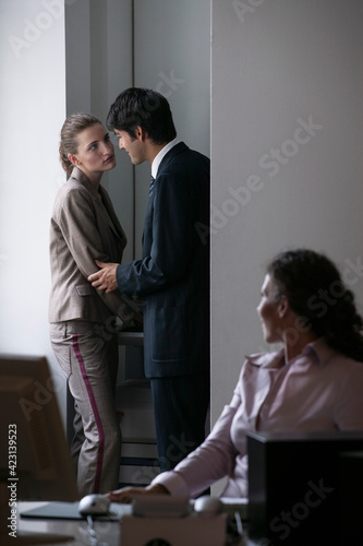 Businessman cornering businesswoman at photocopier in office
