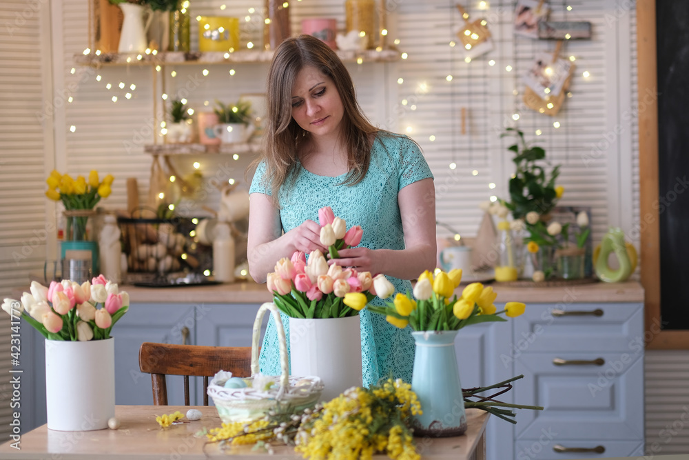 woman decorates her house with flowers. woman collects a bouquet of tulips at home in the kitchen. spring mood