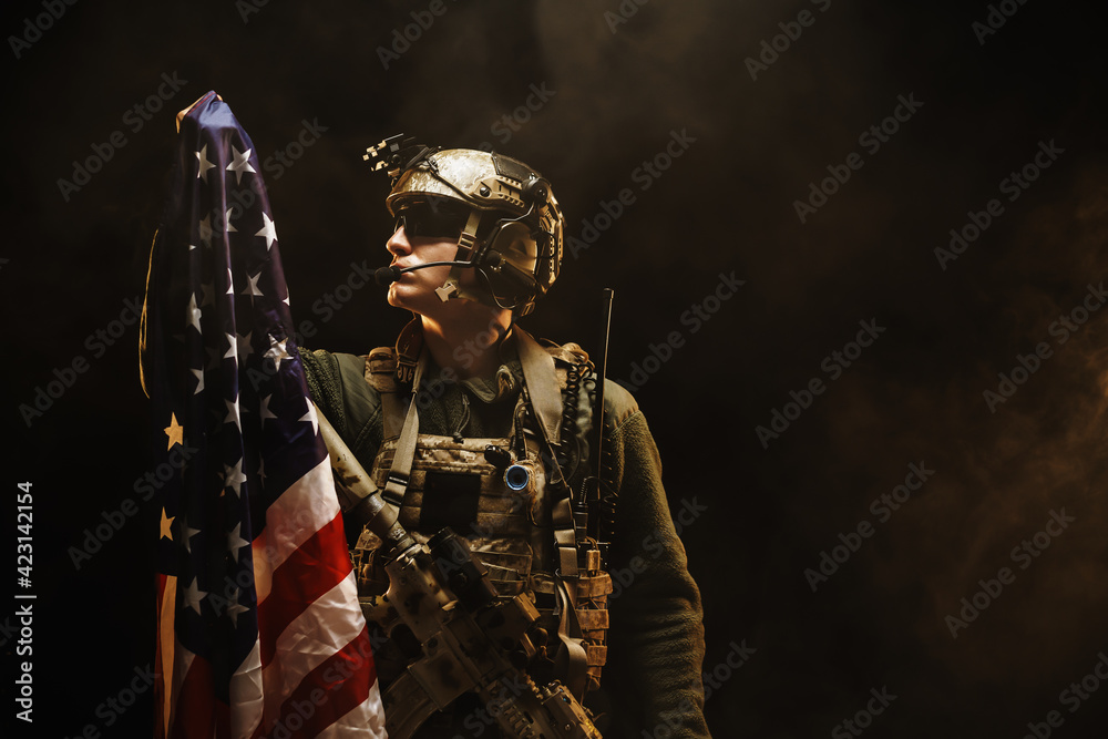 Special forces soldier holding US national flag in the dark Special forces soldier holding US national flag in the dark