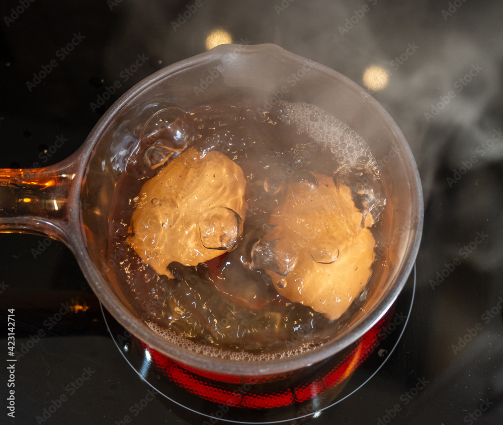 Two eggs boiling in a glass pan on a ceramic hob Two eggs boiling in a glass pan on a ceramic hob