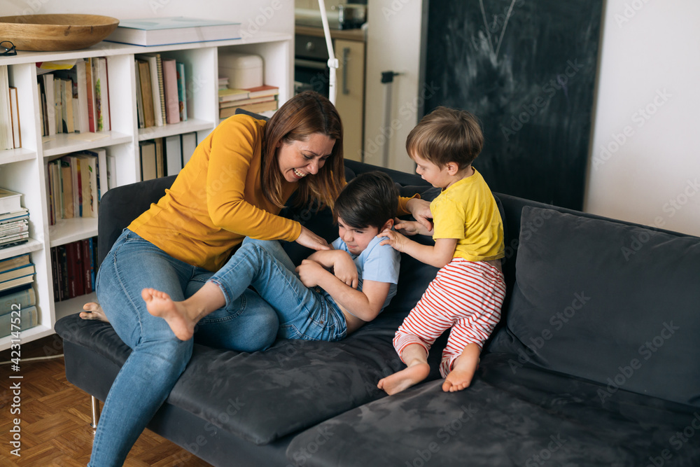 mother hugging and playing with children at home