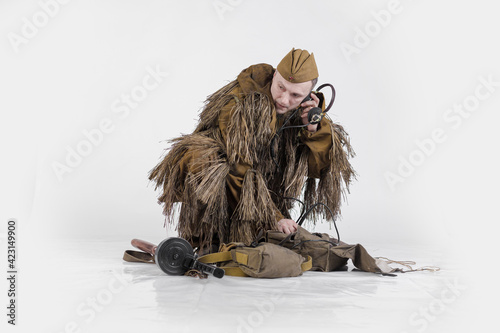 Actor male radio operator soldier of the Soviet army in old military uniform and camouflage clothes In Ghillie Suit during World War II photo