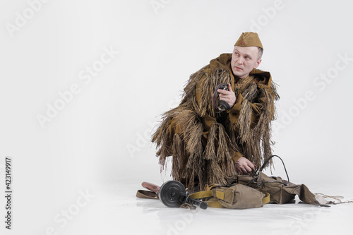 Actor male radio operator soldier of the Soviet army in old military uniform and camouflage clothes In Ghillie Suit during World War II
