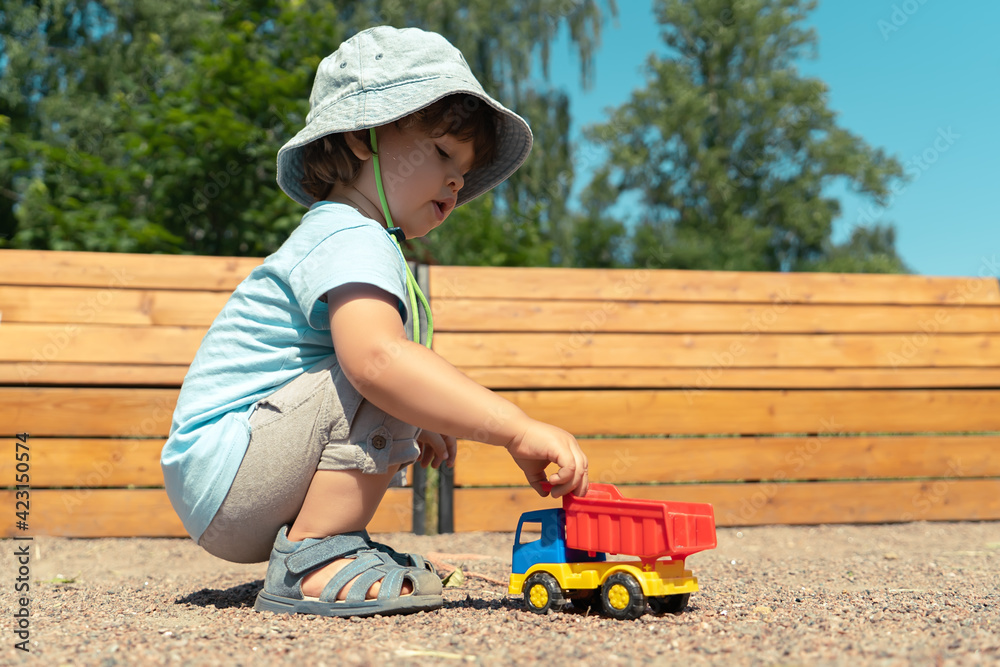 Portrait of a little boy sitting and playing with a toy car outdoors Portrait of a little boy sitting and playing with a toy car outdoors