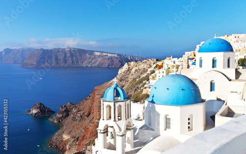 Greece. Santorini Island. Oia village. The Orthodox Church with the traditional blue domes and white plastered walls and blue water of the Aegean Sea