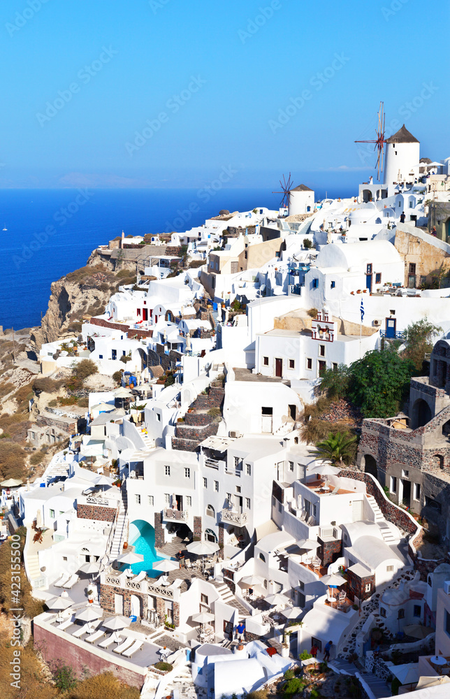 The picturesque village of Oia with white Cycladic houses and a windmill on a hill, Santorini, Greece