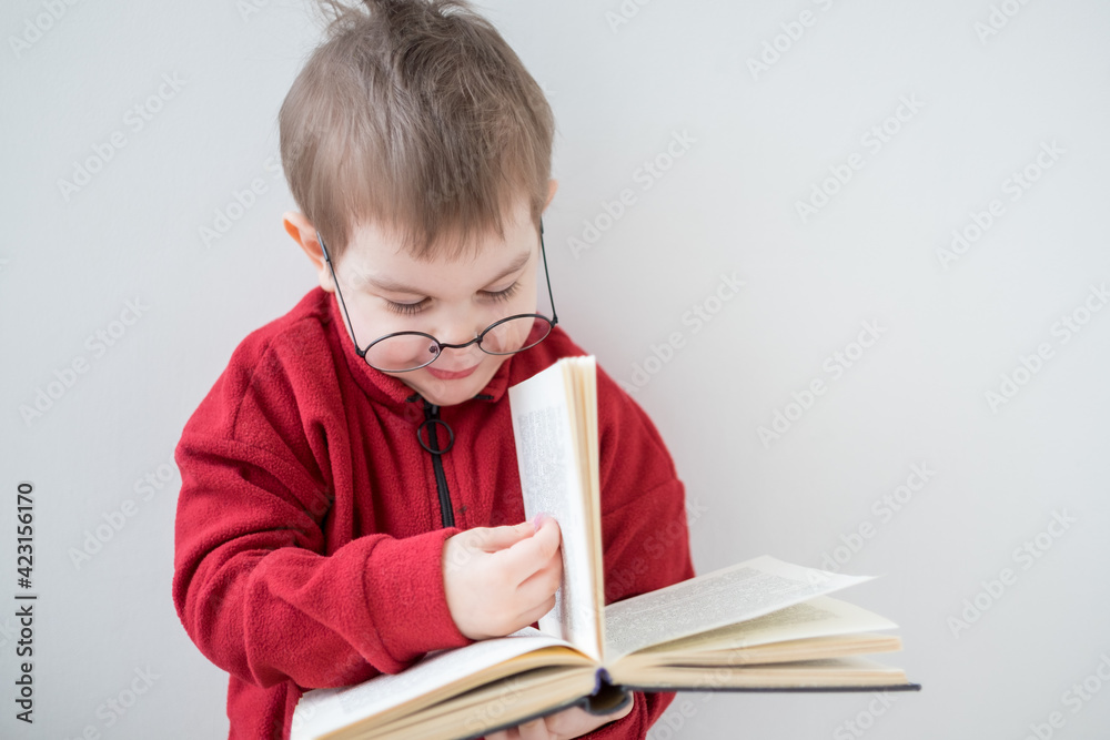 Cute Cheerful Little boy reading a book in glasses. Smart preschooler. Back to school concept Cute Cheerful Little boy reading a book in glasses. Smart preschooler. Back to school concept