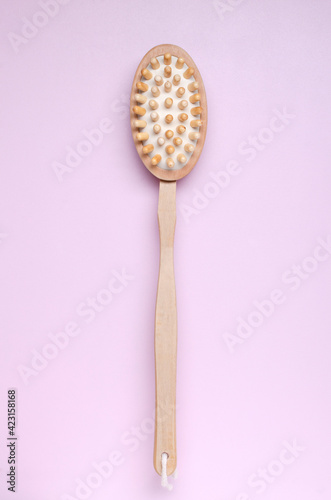 Vertical image.Wooden brush for dry massage on the bright pink surface