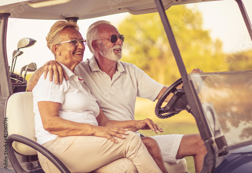 Golfers couple are riding in a golf cart and talking.