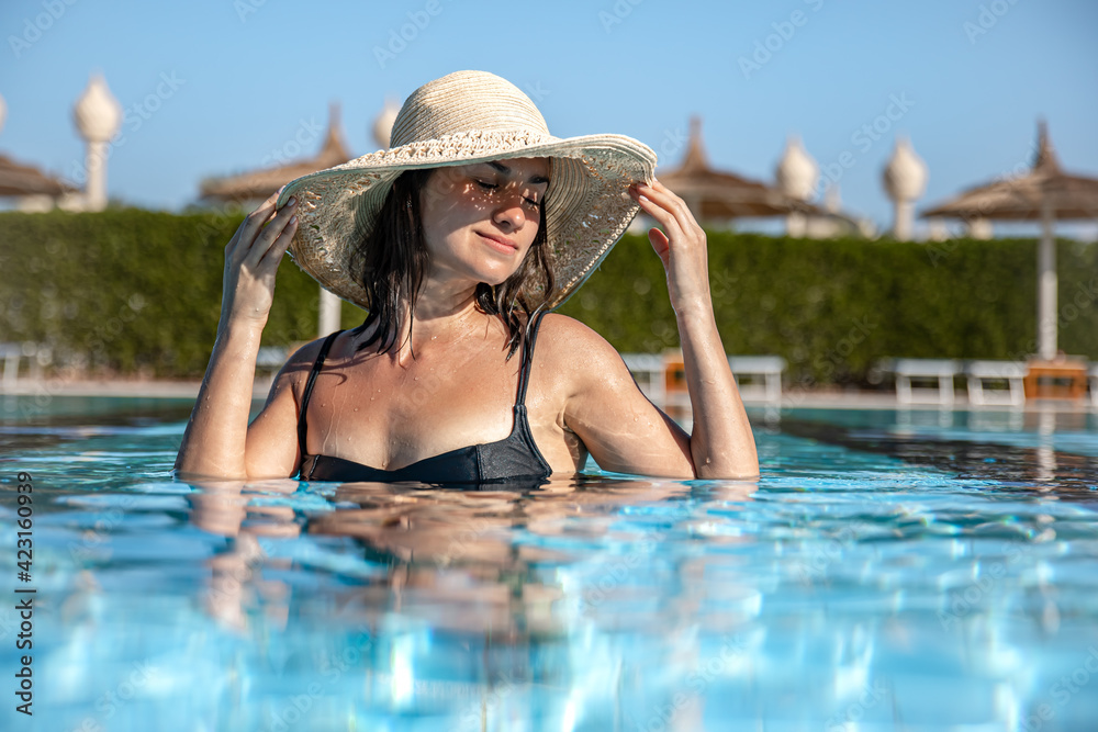 Portrait of a young woman bathing in the pool on a hot summer day.