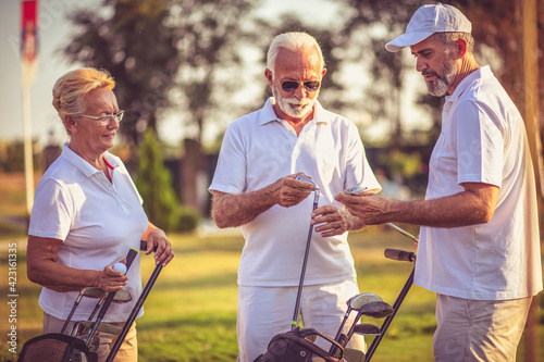 Senior friends on golf court talking.