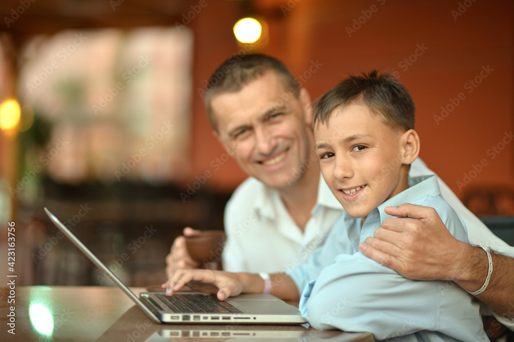 son and father using laptop at home son and father using laptop at home