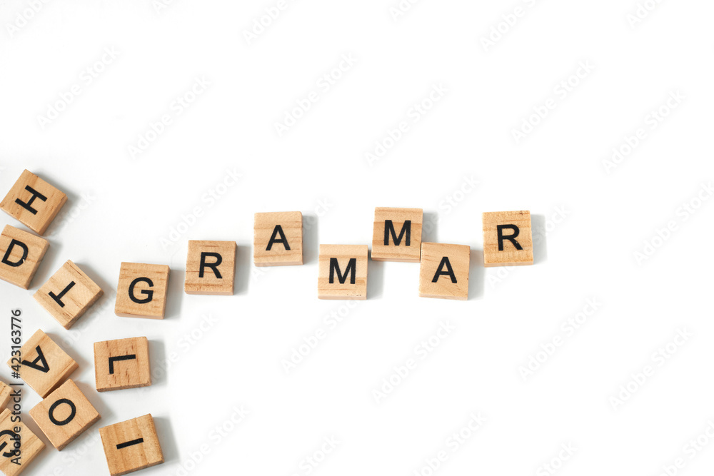Top view of word grammar made of square wooden tiles with the English alphabet scattered on a white background with space for text. The concept of thinking development, grammar. Top view of word grammar made of square wooden tiles with the English alphabet scattered on a white background with space for text. The concept of thinking development, grammar.