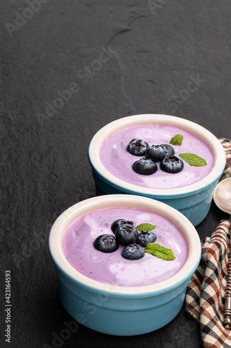 Fresh yoghurt with blueberry in ceramic bowl on black stone background