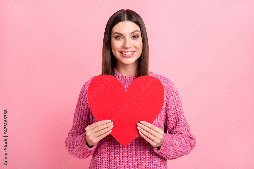 Portrait of brunette optimistic girl hold heart wear pink sweater isolated on crimson color background Portrait of brunette optimistic girl hold heart wear pink sweater isolated on crimson color background