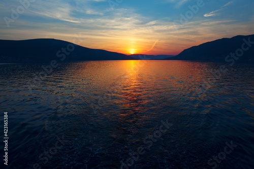 Generic sunset over the sea and mountains . Sundown reflection in the sea water