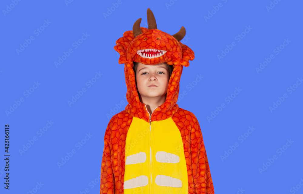 boy in dragon pajamas stands at attention on a blue background