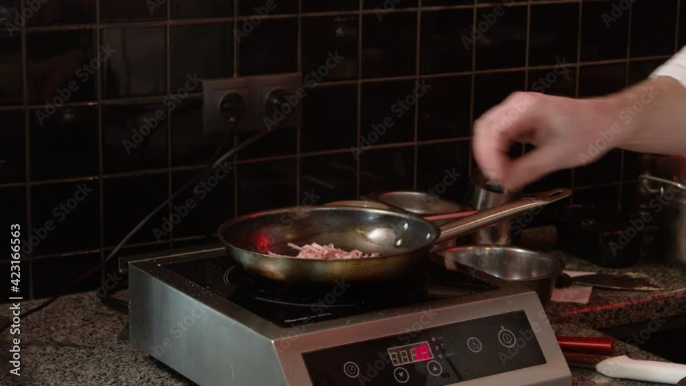 male hands put bacon in a frying pan on an electric whip