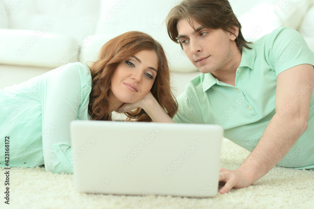 Happy young couple looking at laptop at home Happy young couple looking at laptop at home