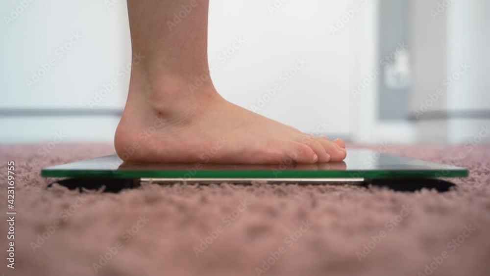 The legs of the child on the scales. A little girl gets bare feet on
