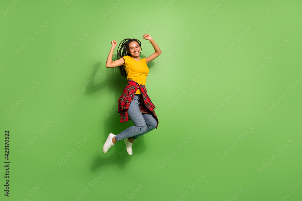 Full length body size view of pretty funky cheerful girl jumping rejoicing having fun isolated over bright green color background Full length body size view of pretty funky cheerful girl jumping rejoicing having fun isolated over bright green color background